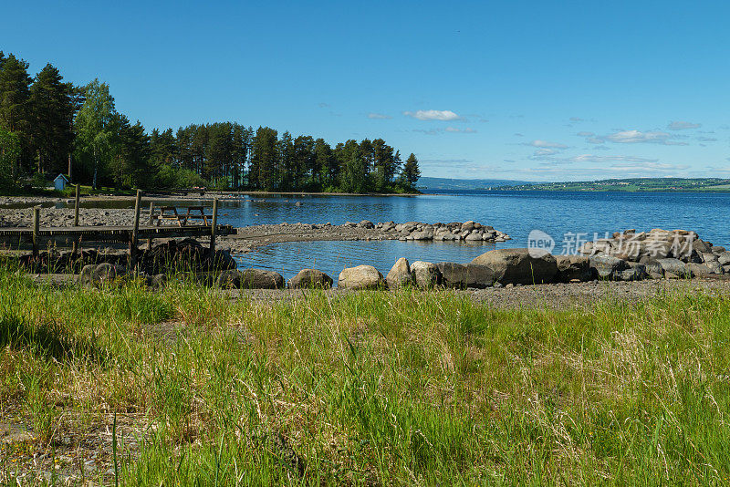 Lake Mjøsa near Hamar. In the foreground the beach with stones and pebbles. Lake Mjøsa is the largest lake in Norway. Seen on the pilgrimage path St. Olavsweg from Oslo to Trondheim.